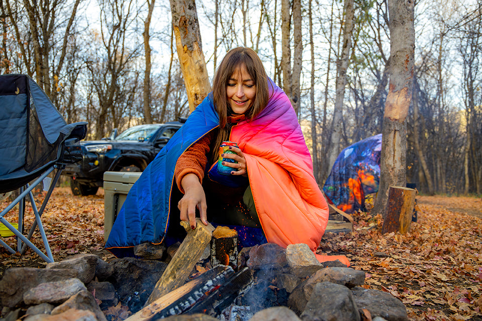 Rumpl blanket wrapped around a woman at a campfire