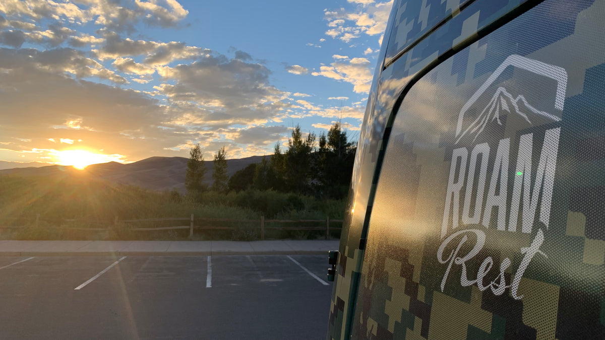 RoamRest camo van on the road at sunset