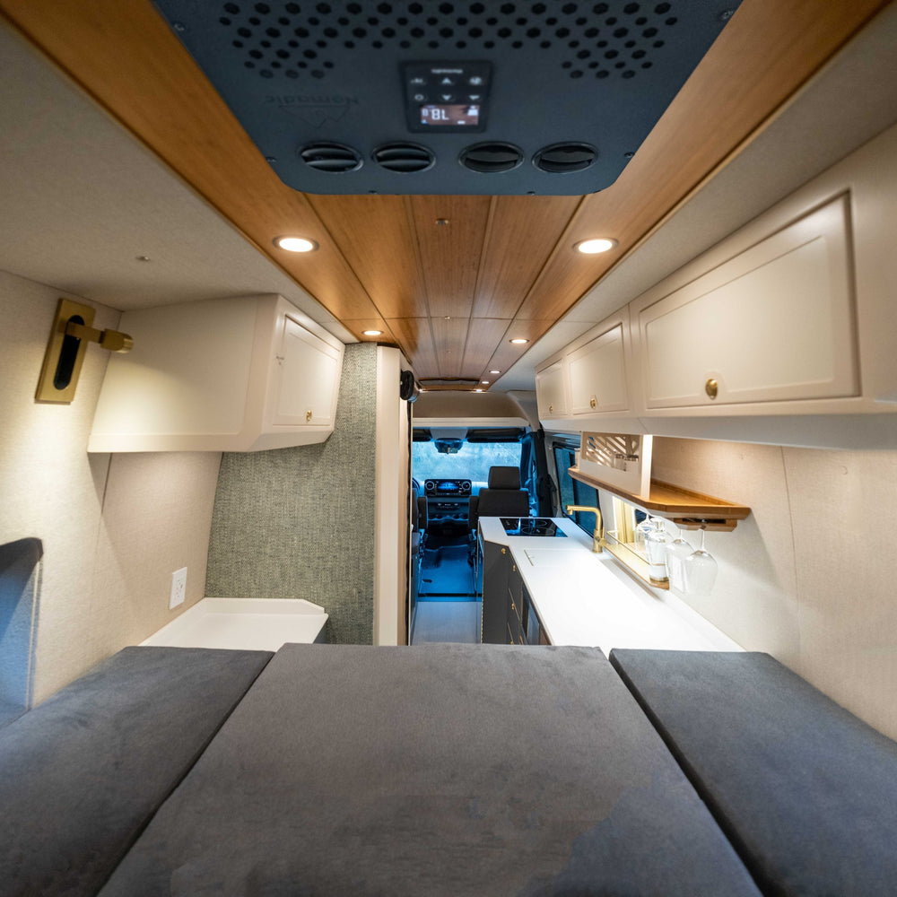 Interior of a modern RV with kitchen area, seating, and overhead storage.